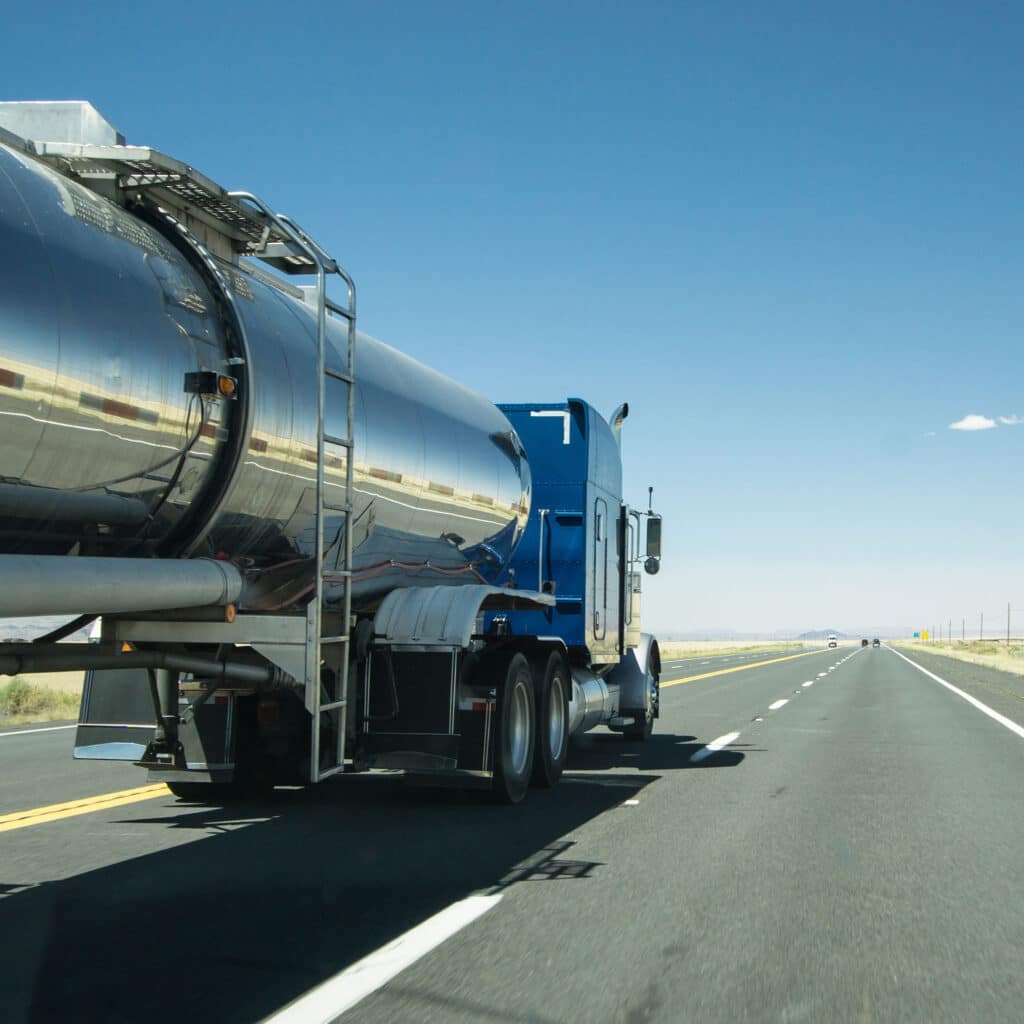 truck with a silver tank trailer passing a passenger car on a highway
