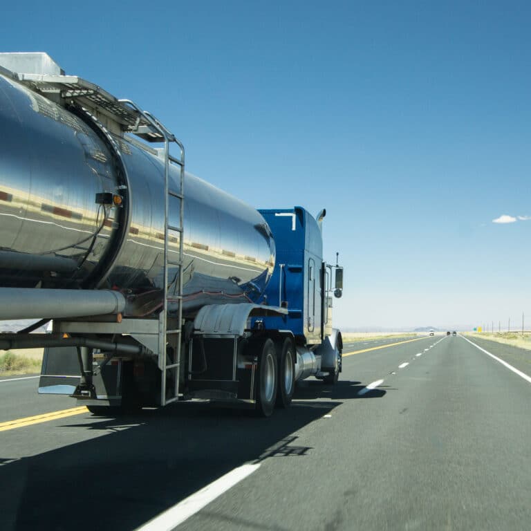 truck with a silver tank trailer passing a passenger car on a highway