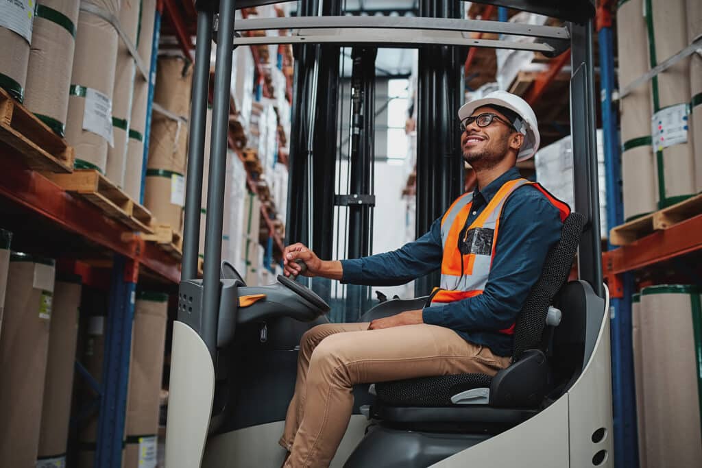 African forklift driver focused on carefully transporting stock from shelves