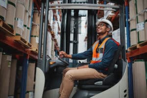 African forklift driver focused on carefully transporting stock from shelves