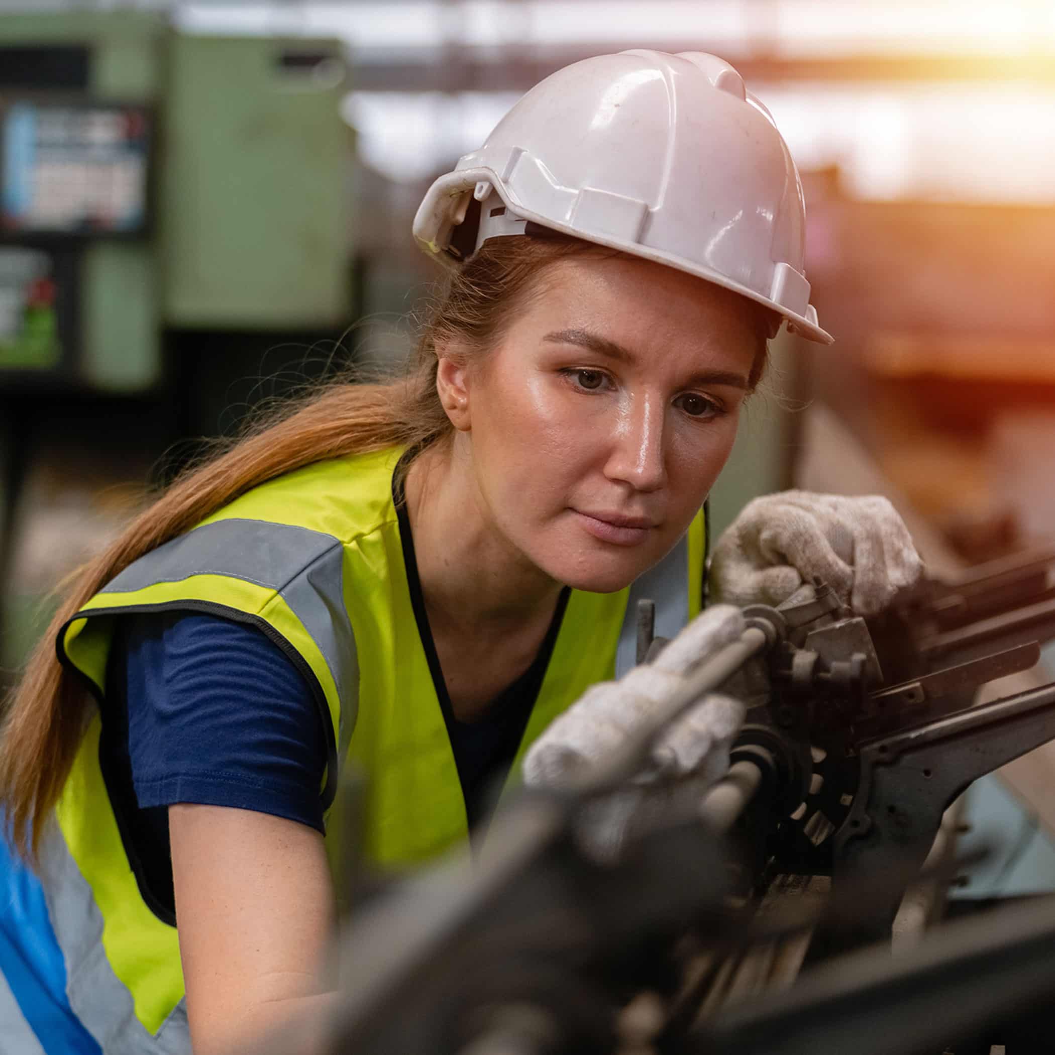 woman engineer wear hardhat working at machine in factory