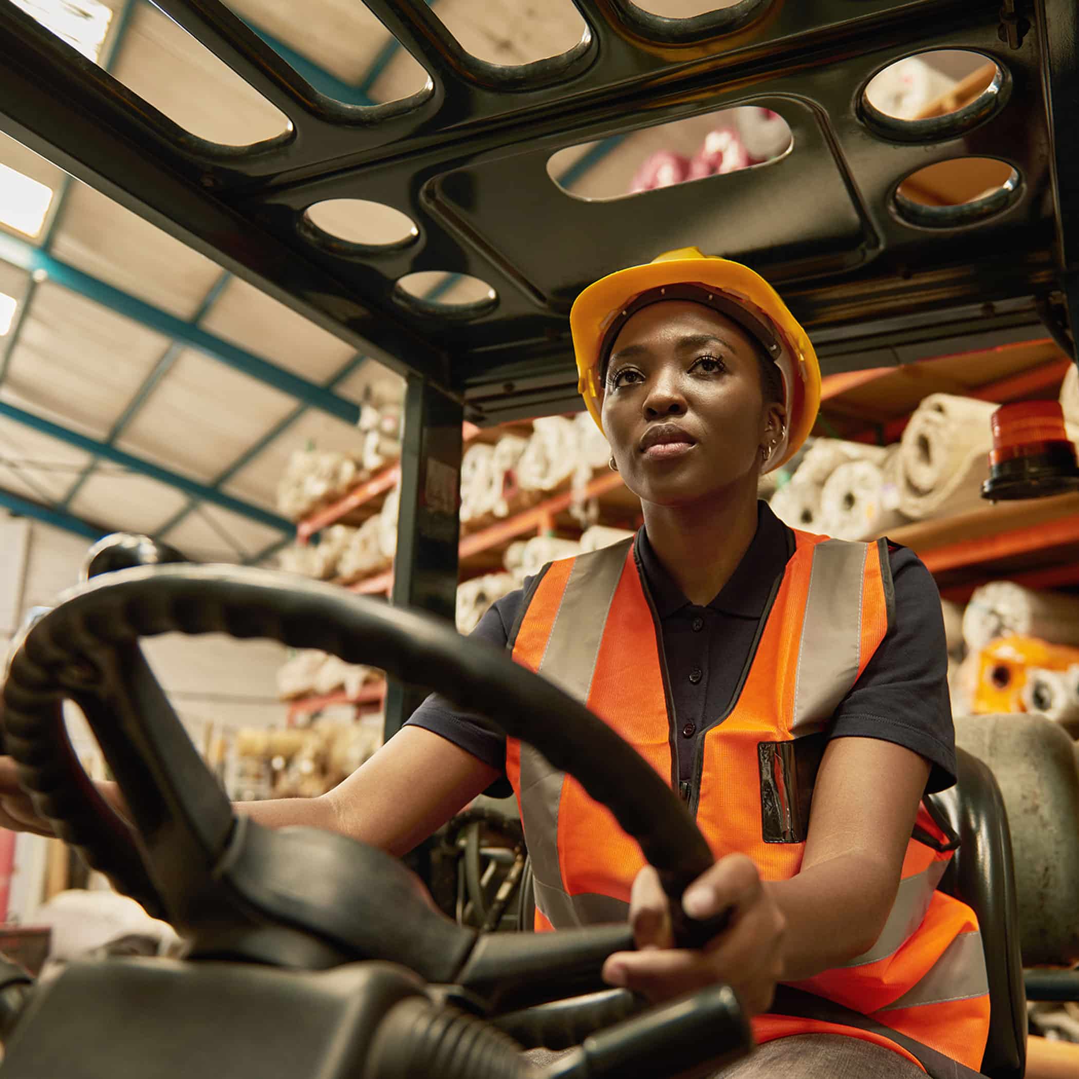 Young African female forklift operator driving around a warehouse